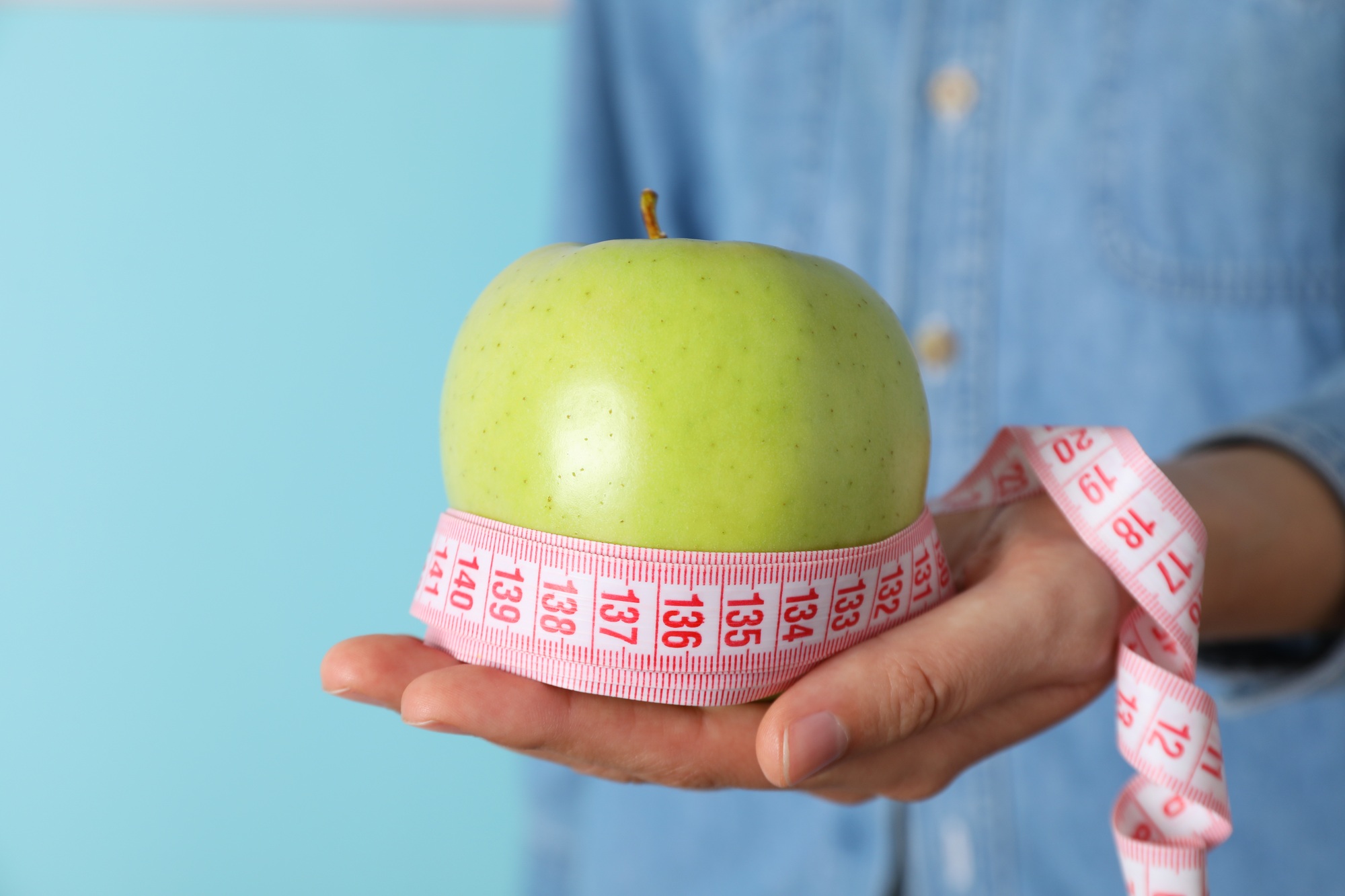 Concept of weight loss and healthy nutrition with apple and measuring tape